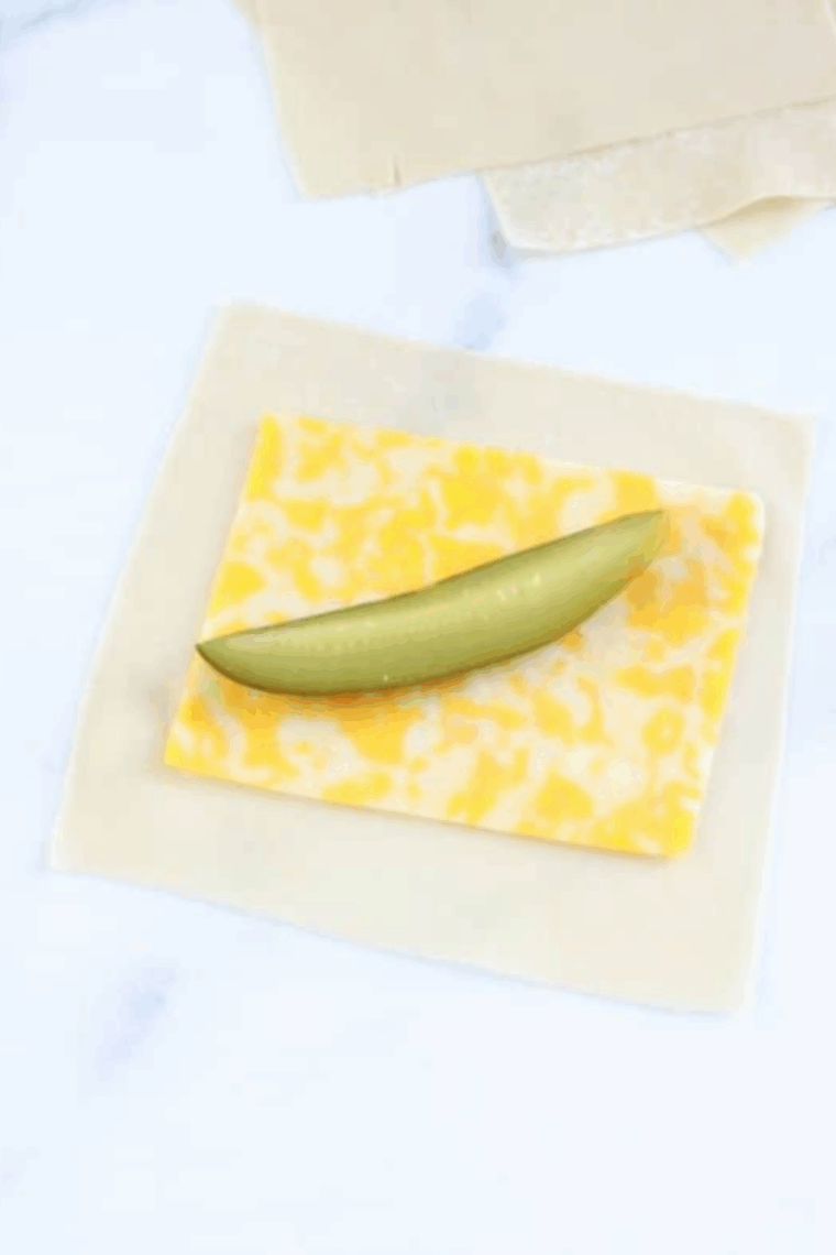 Placing cheese and drained pickle on egg roll wrapper and sealing edges with water.