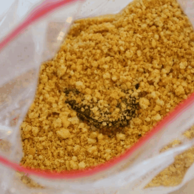 Pickles being coated in seasoned breading mixture by hand.