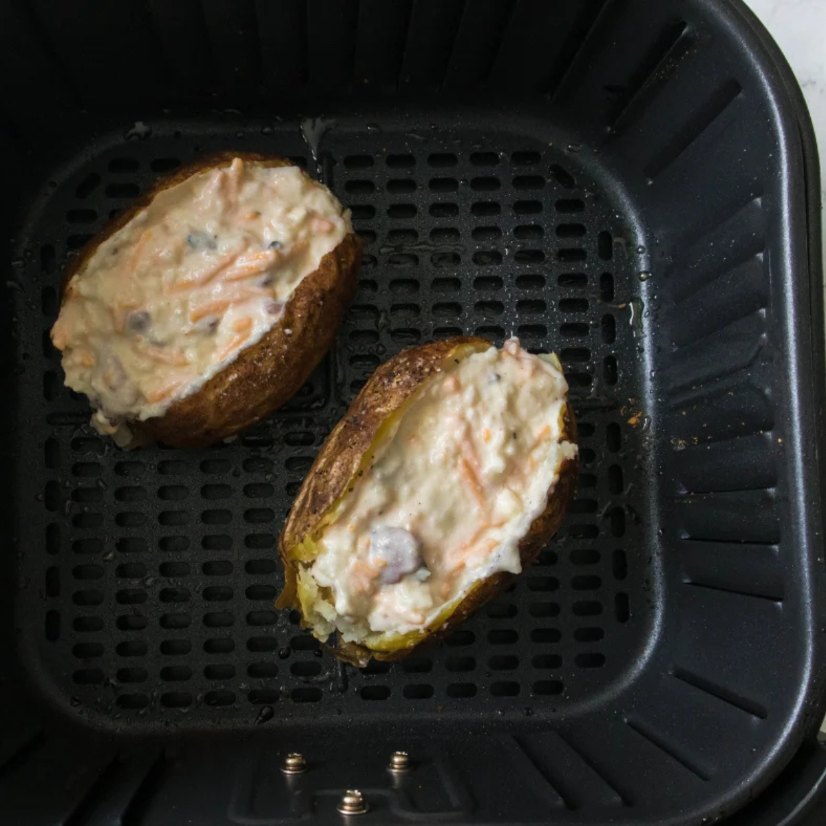 Stuffed potato halves in an air fryer basket before the second bake