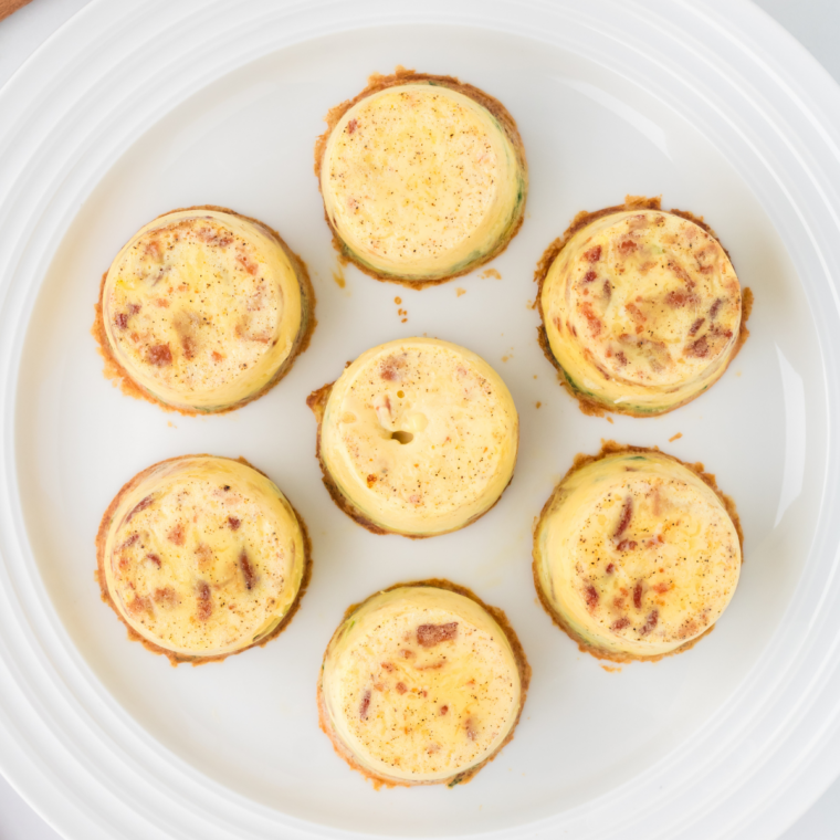Air fryer veggie egg bites with set, no-longer-jiggly centers and pale golden tops on a white plate.