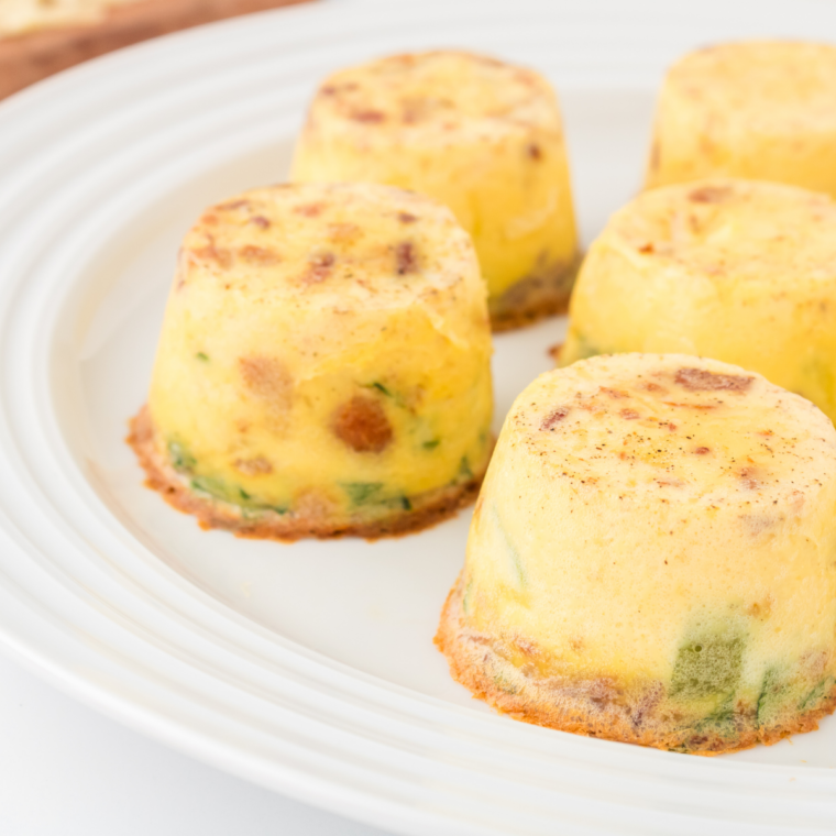 Air fryer veggie egg bites on a white plate, golden and fluffy with visible bell peppers and onions