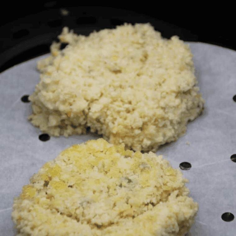 Frozen potato pancake placed on parchment paper in the air fryer, ready to cook at 380°F, flipped halfway through.