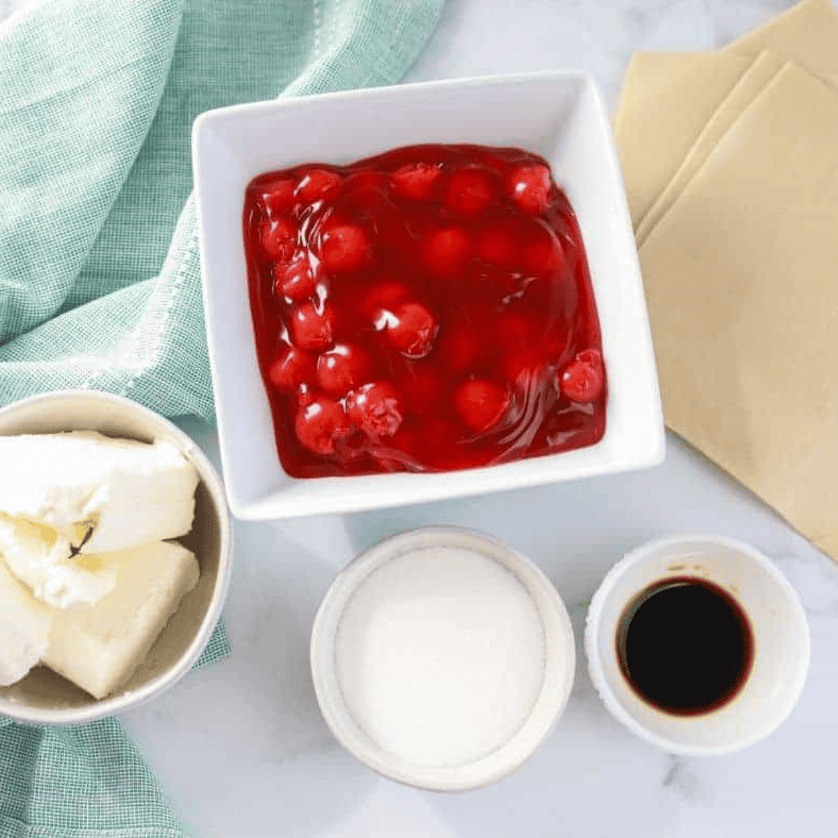 Ingredients needed for Easy Air Fryer Cherry Cheesecake Egg Rolls on kitchen table.