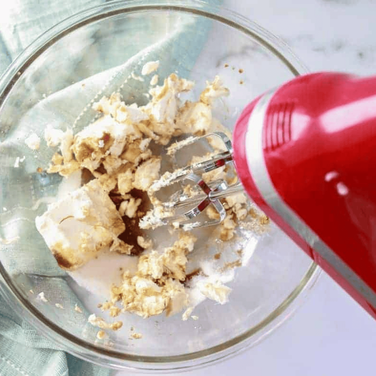 Mixing bowl with creamy cheesecake filling made from cream cheese, sugar, and vanilla, blended until smooth and creamy.
