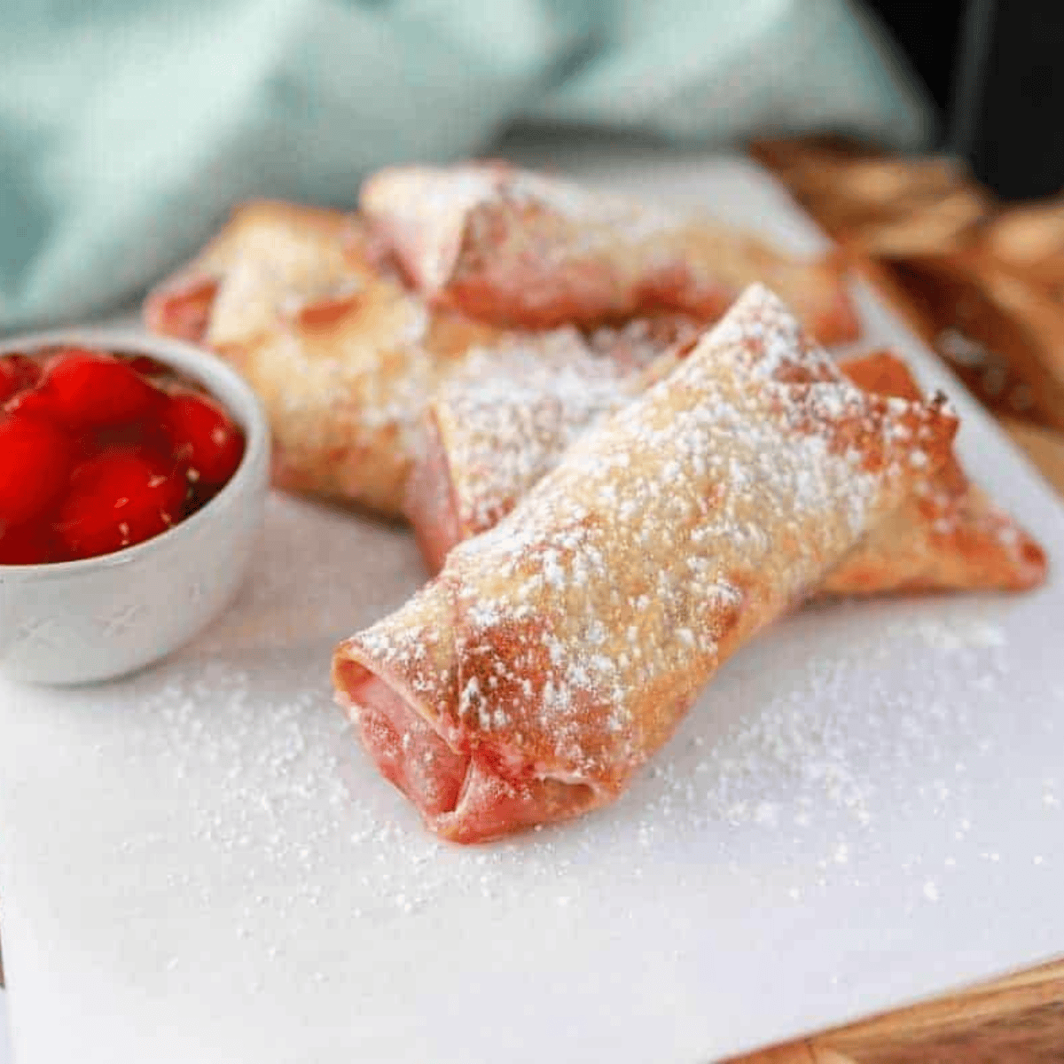 Crispy air fryer cherry cheesecake egg rolls with golden-brown wrappers and cherry filling inside.