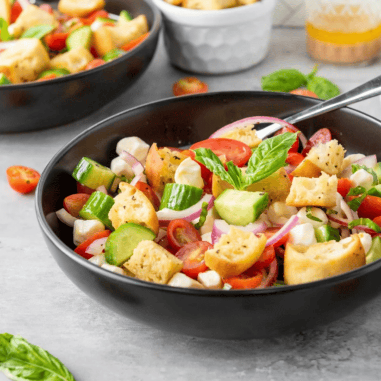 Air fryer grilled panzanella salad with toasted bread cubes, tomatoes, cucumbers, onions, and fresh basil in a bowl