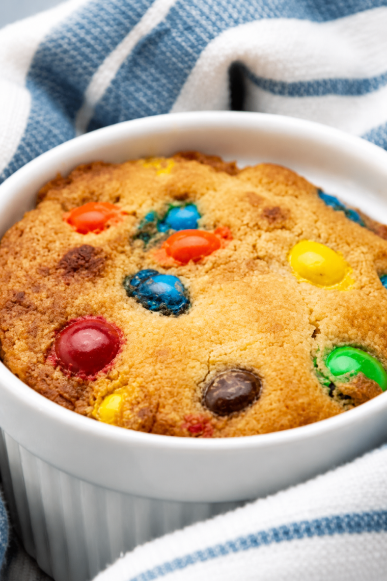 Air fryer M&M mug cake in a white ramekin, topped with colorful M&M candies