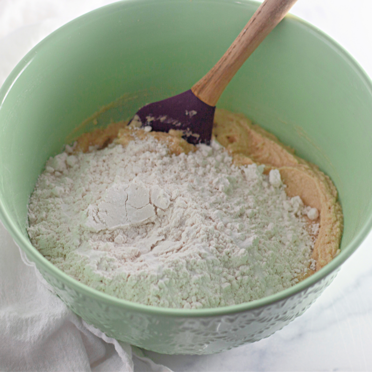 Brown sugar, butter, egg yolk, flour, and vanilla stirred into M&M mug cake batter in a small bowl