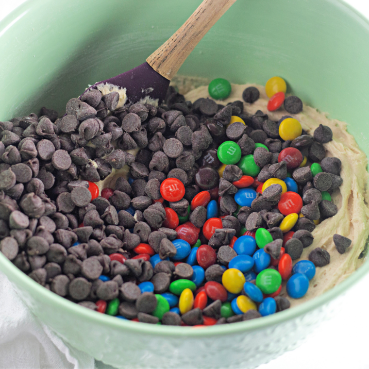 Colorful M&M candies folded into mug cake batter, a few reserved for the top