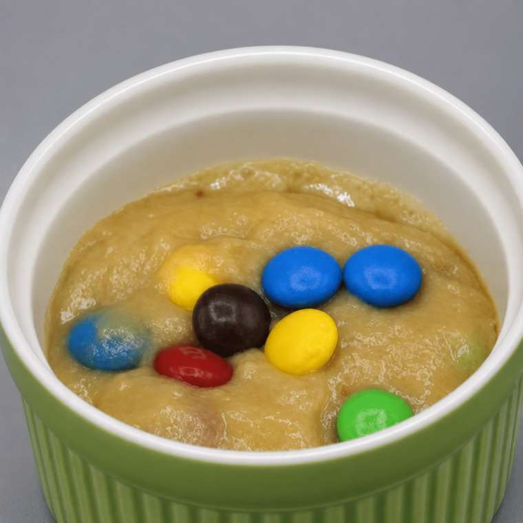 M&M mug cake batter poured into a greased ramekin, filled two-thirds full