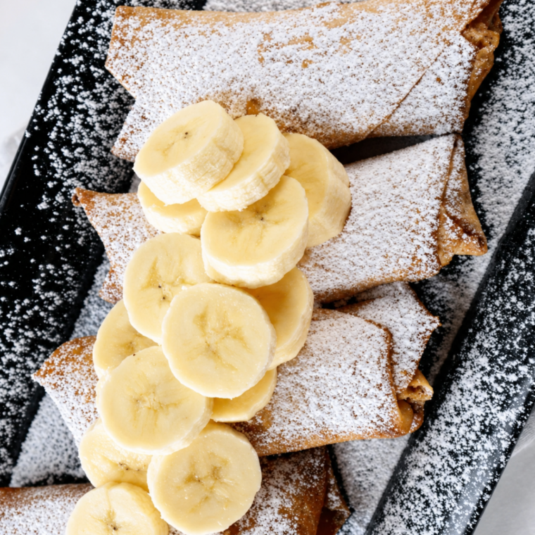 Air fryer peanut butter banana egg rolls topped with fresh banana slices