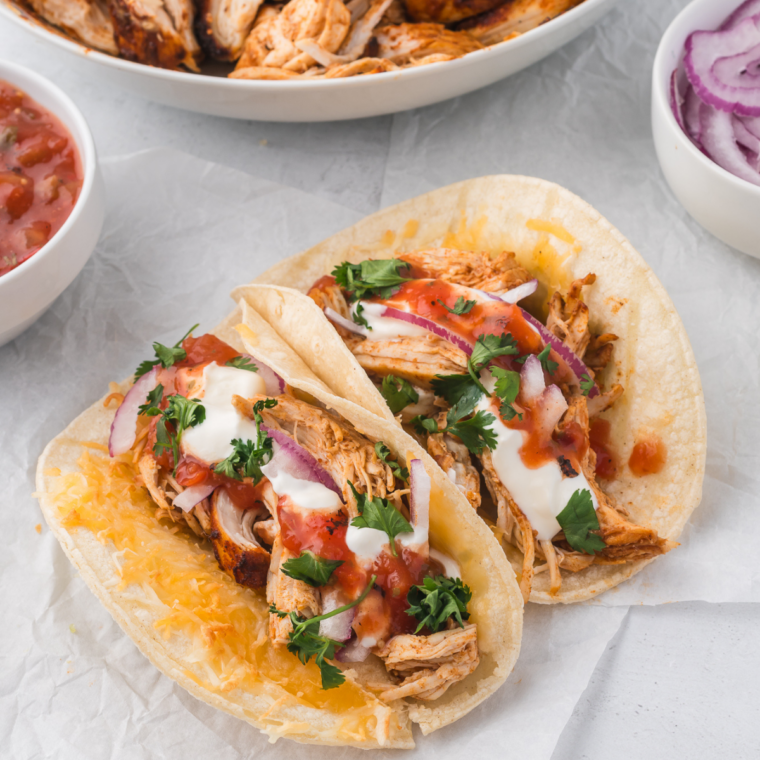 Blackstone Mojo chicken tacos sizzling on a flat top griddle with fresh toppings