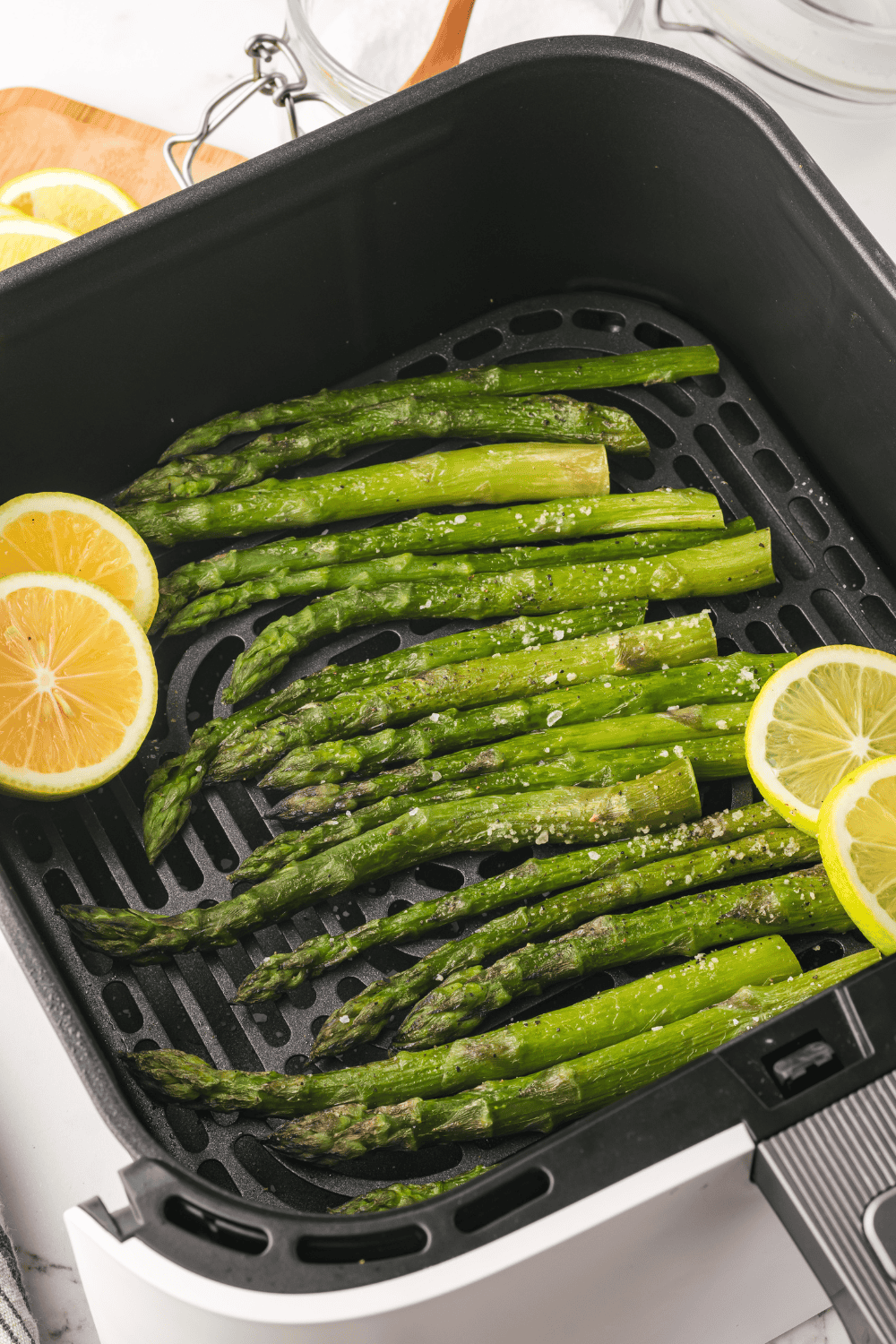 Crispy air-fried frozen asparagus served hot on a plate with lemon.