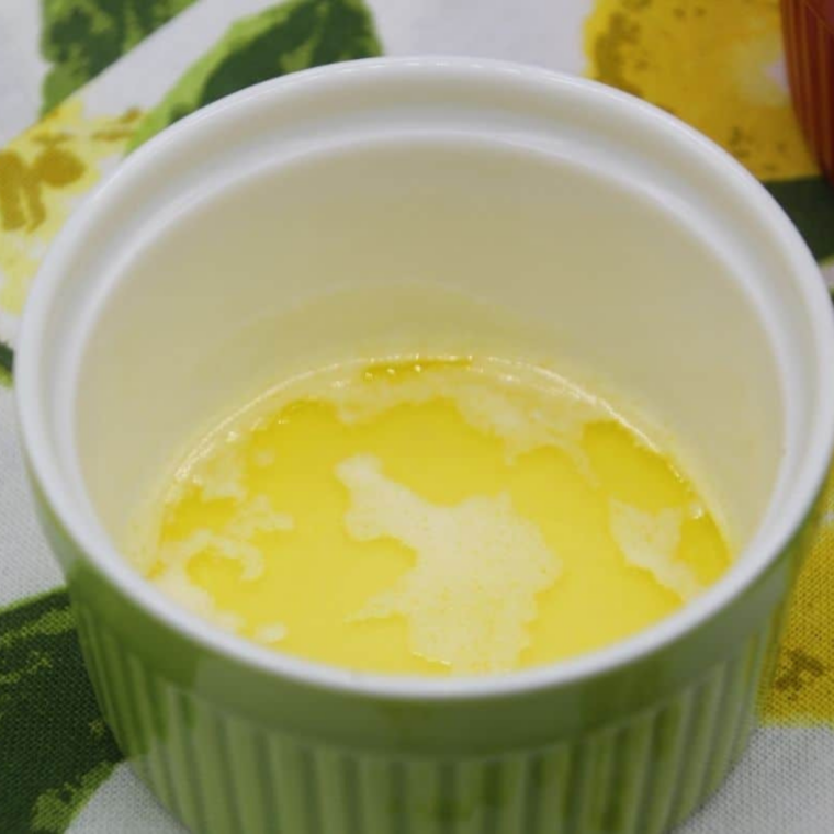 Melted butter poured into a white oven-safe ramekin for air fryer banoffee pie