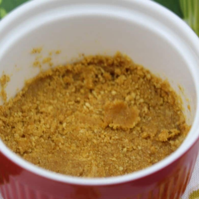 Graham cracker crumbs pressed into the bottom and sides of a ramekin with a spoon