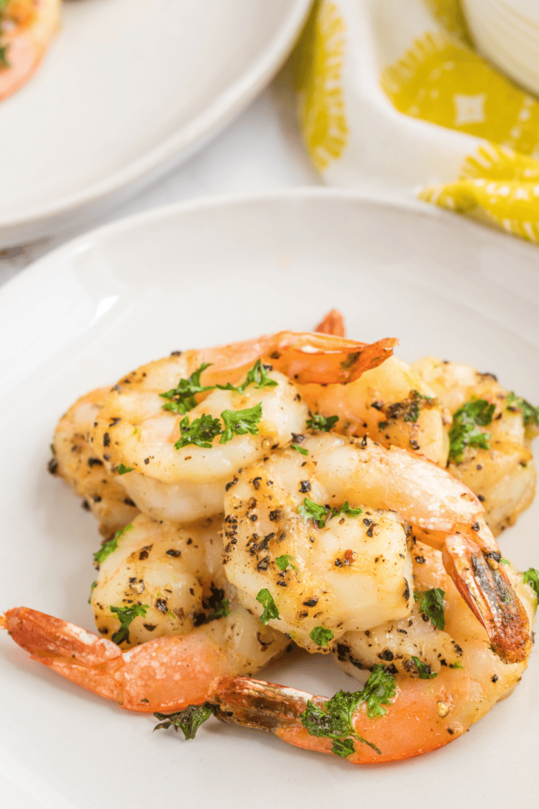 Crispy lemon pepper shrimp plated with lemon wedges and garnished with fresh herbs.