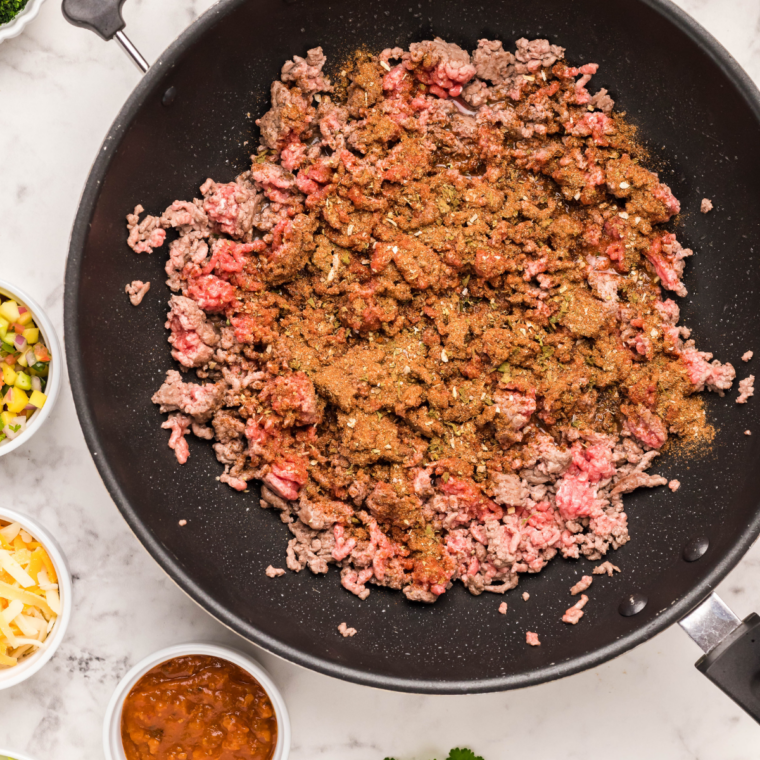 Browning seasoned ground beef with taco seasoning and sofrito in a skillet for mini taco boats