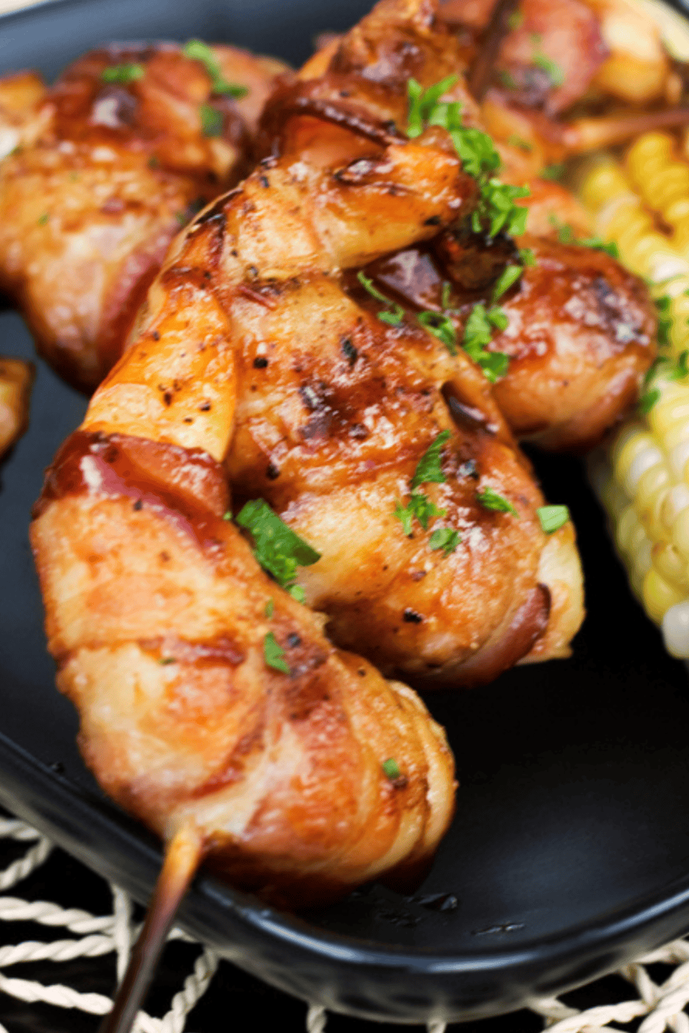 Crispy bacon-wrapped shrimp glazed with BBQ sauce, served on a platter with lemon wedges.