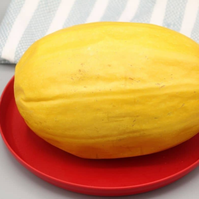 Whole spaghetti squash, water, kosher salt, and olive oil on a marble counter