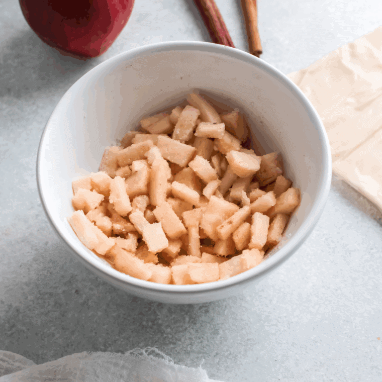 Spiced apple filling resting in a small mixing bowl before assembling