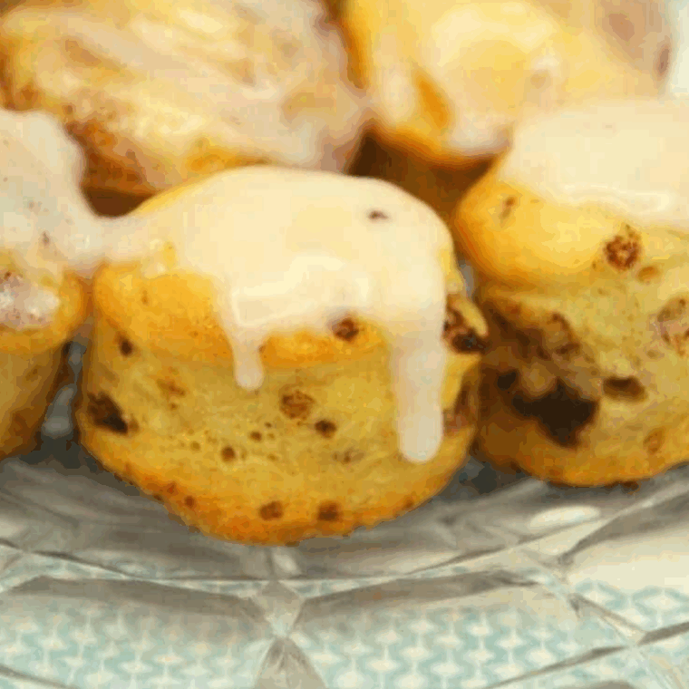 Golden, gooey air fryer cinnamon roll bites drizzled with sweet glaze on a plate.