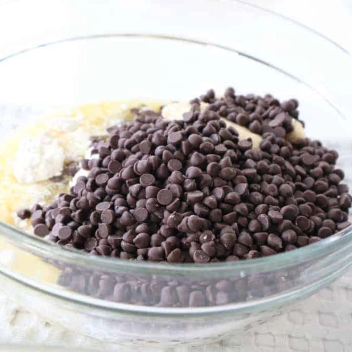 Melted butter, brown sugar, and granulated sugar being stirred together in a large glass mixing bowl