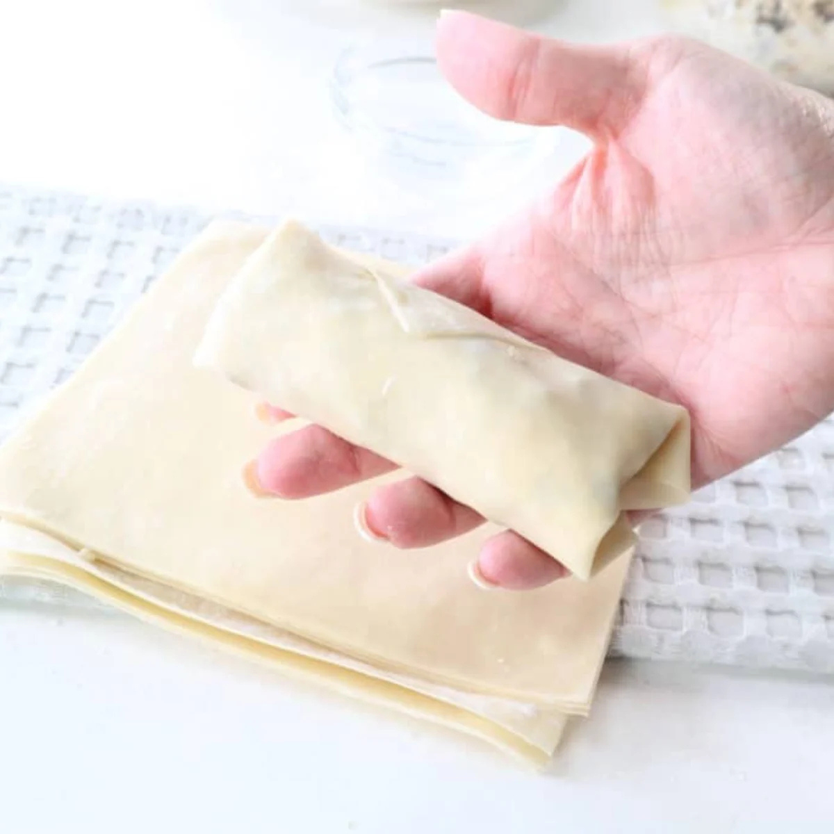 Sealed cookie dough egg rolls lined up seam side down on a cutting board