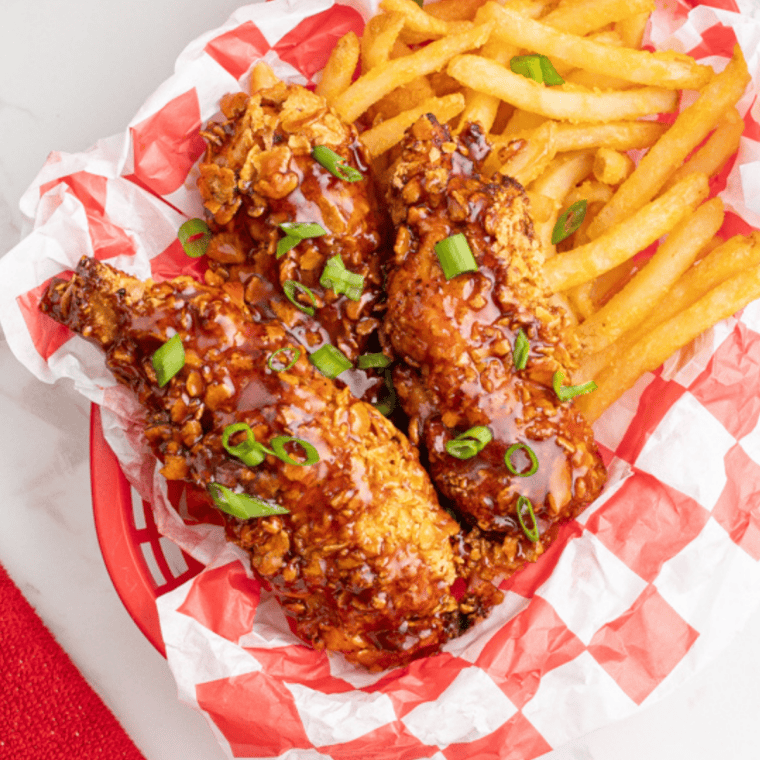 Crispy golden chicken tenders cooked in air fryer, marinated in pickle brine, served with dipping sauce on a plate.