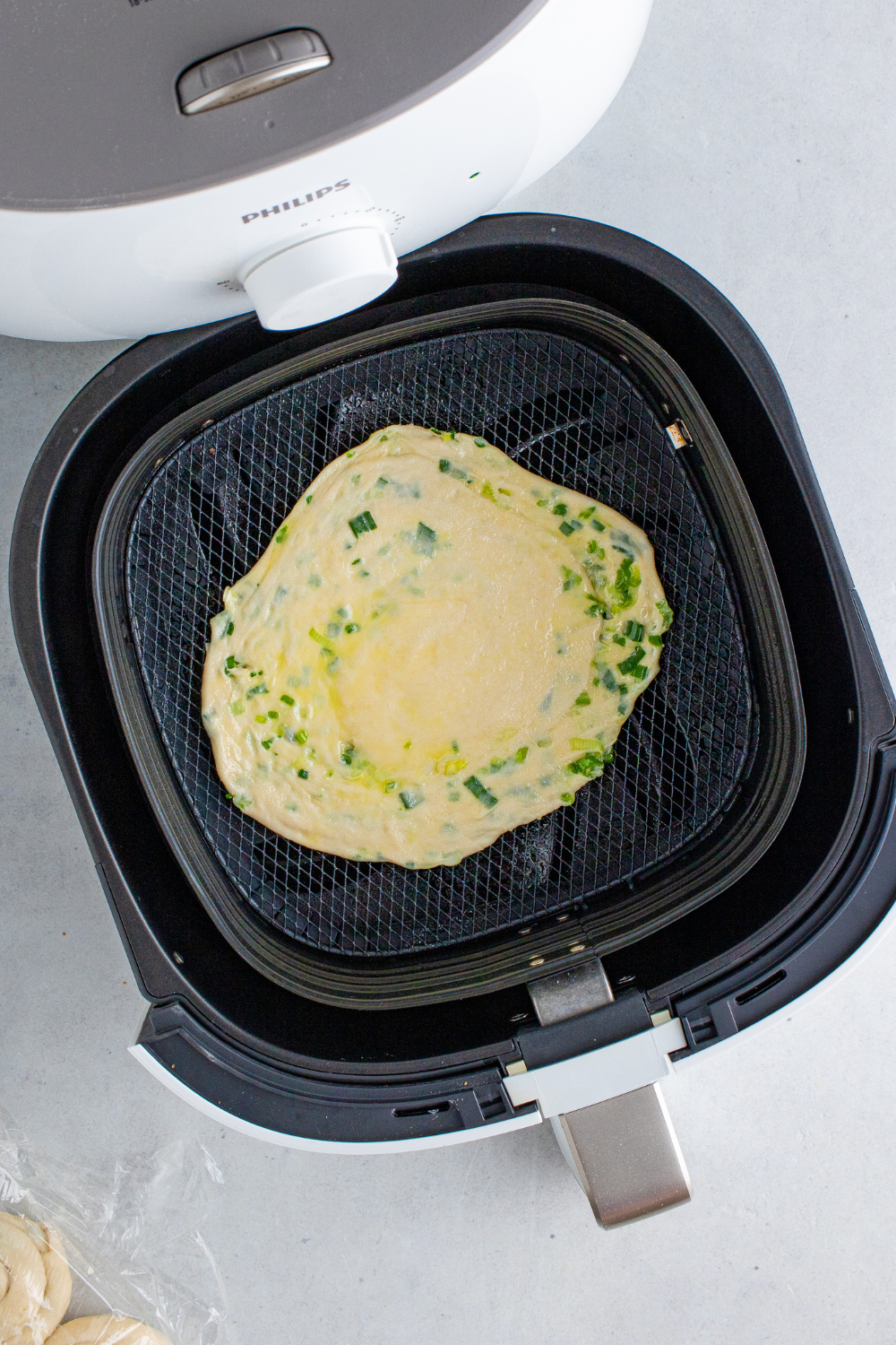 Flattened dough spiral being rolled into scallion pancake circle