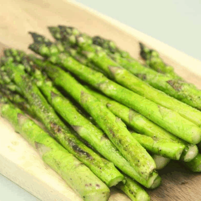 Blackstone asparagus with charred edges and seasoning cooking on a flat top griddle