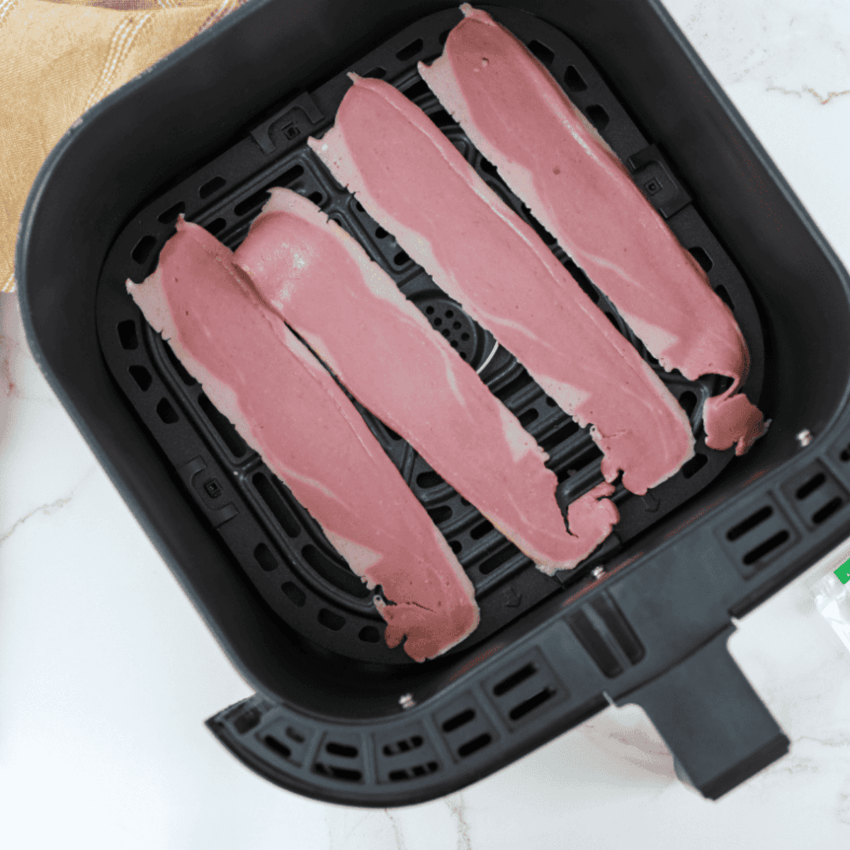 Alt tag: Turkey bacon strips on parchment paper sprinkled with brown sugar, ready to be air fried for a sweet and crispy candied finish.