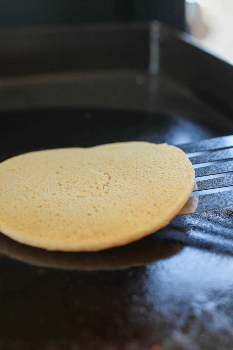 Pancakes mid-flip showing golden underside.