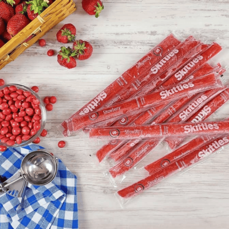 Crushing frozen Strawberry Skittles pops and collecting the contents in a medium bowl.