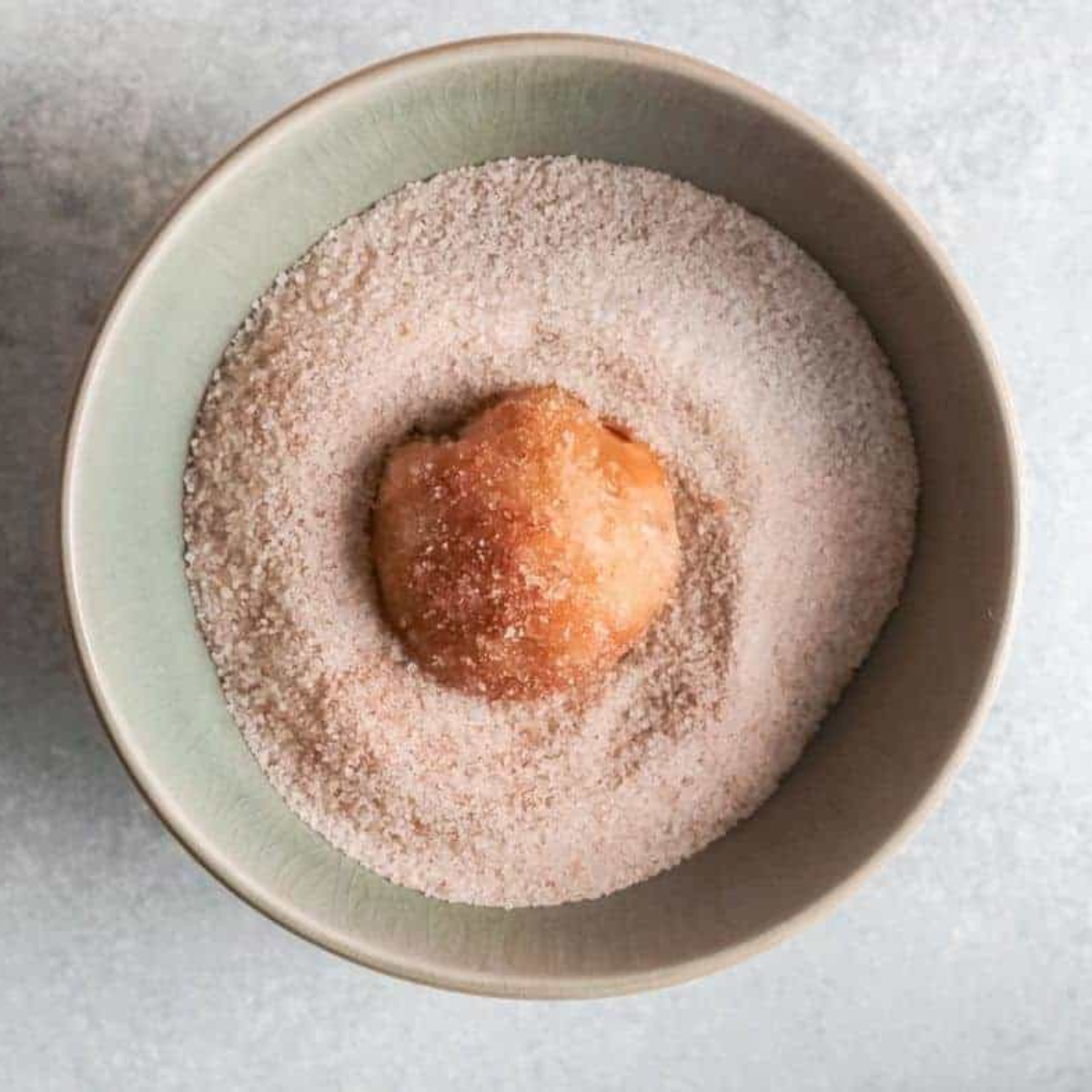 Coating air fryer apple pie bombs in butter and cinnamon sugar