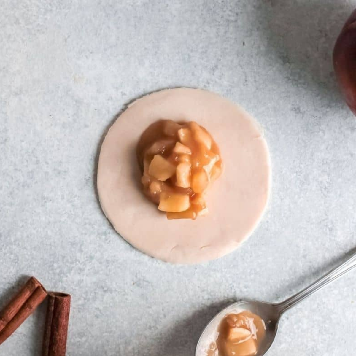 Rolling biscuit dough and adding apple pie filling to make apple pie bombs