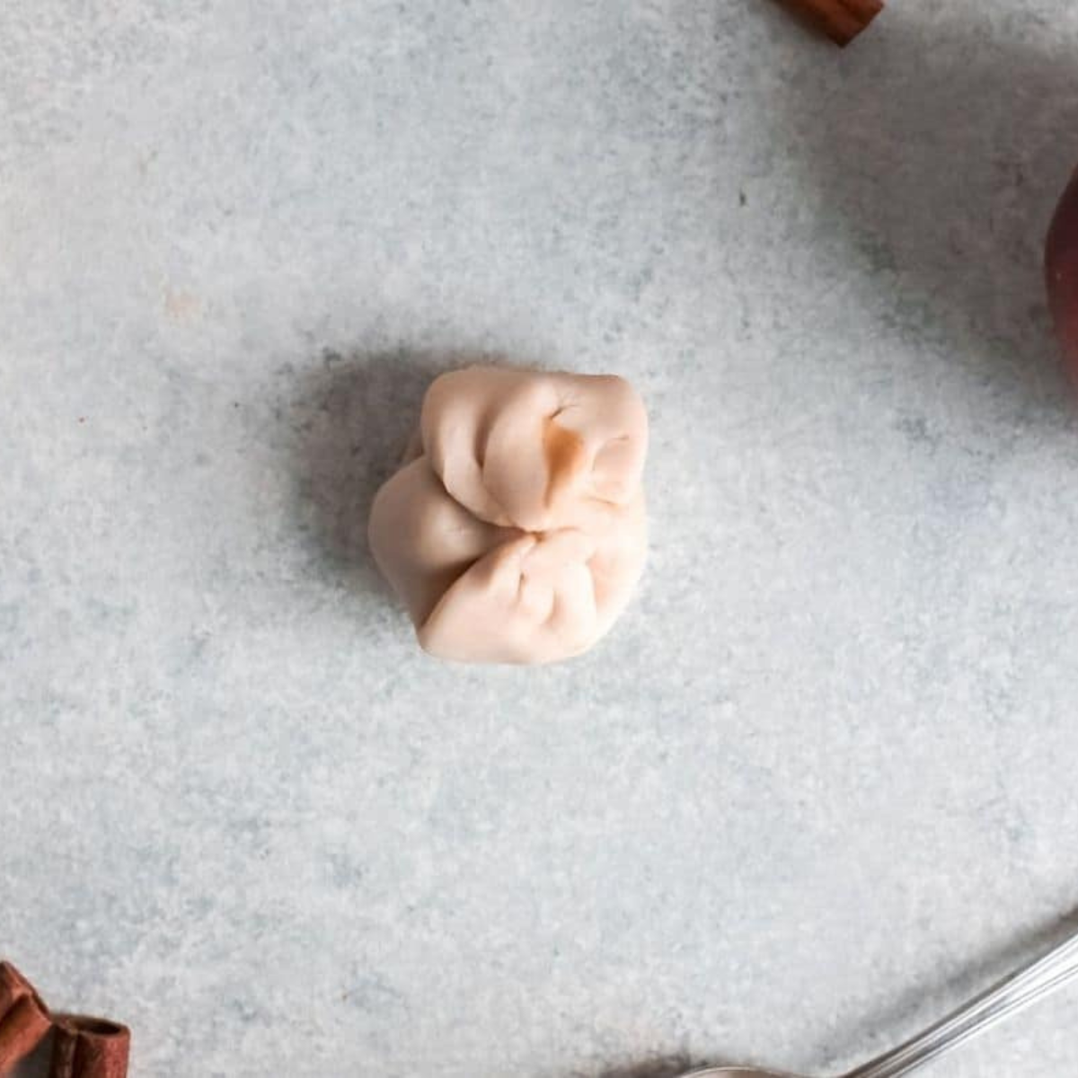Pinching biscuit dough to seal a cinnamon sugar stuffed apple donut