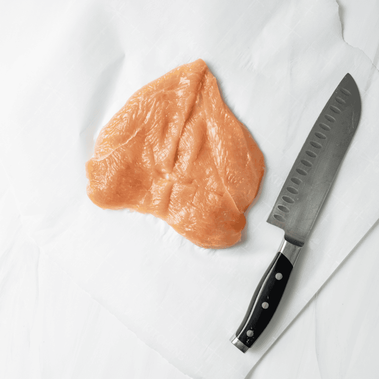 Chicken breasts pounded evenly with meat mallet between plastic wrap, seasoned with salt and pepper for even cooking.