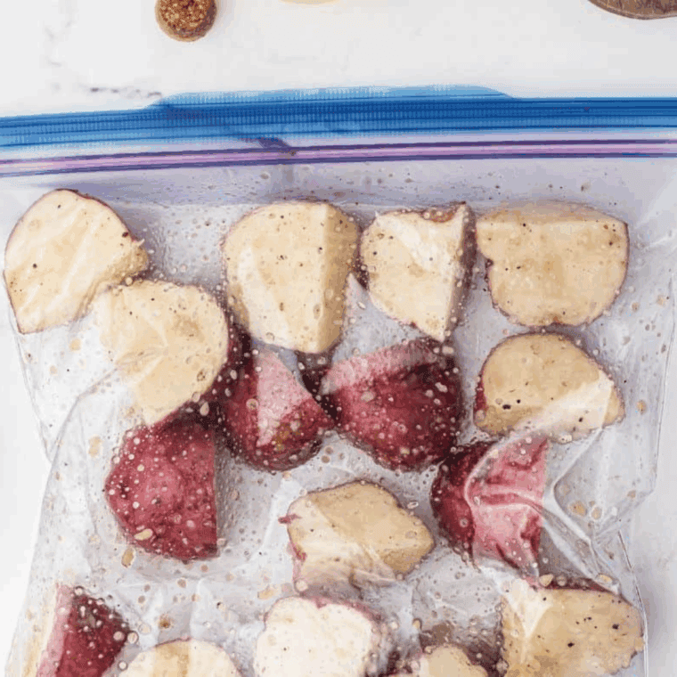 Place diced potatoes in a resealable bag with olive oil, garlic, salt, and pepper, then shake to coat evenly.