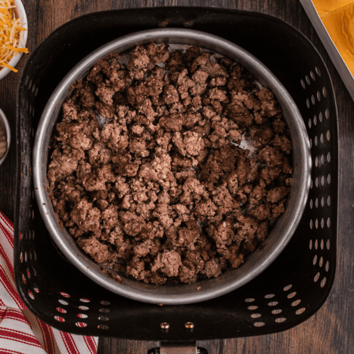Cooked ground beef in an air fryer basket, ready to use in recipes