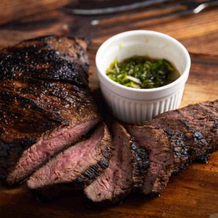 Rest Before Serving: Cooked tri-tip steak slices resting on cutting board before serving.
