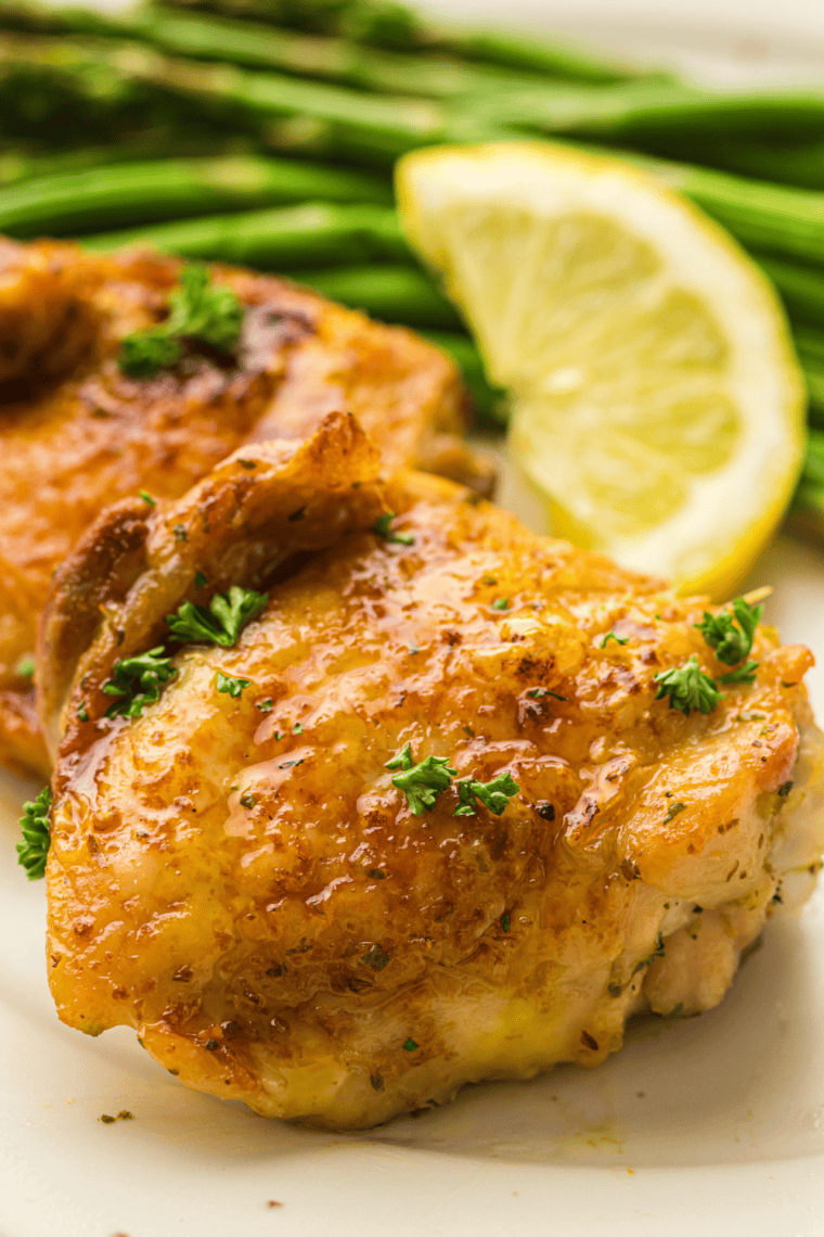 Crispy golden-brown chicken thighs cooked in a Ninja Crispi air fryer, garnished with fresh herbs on a plate.