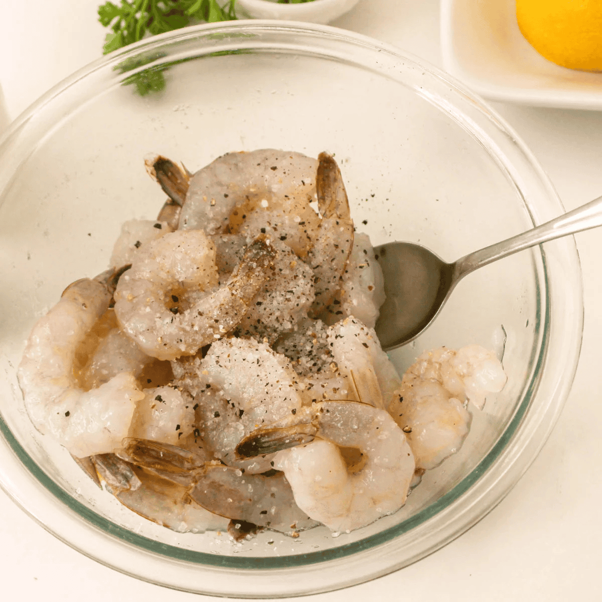 Patting raw peeled shrimp dry with paper towels on a cutting board.
