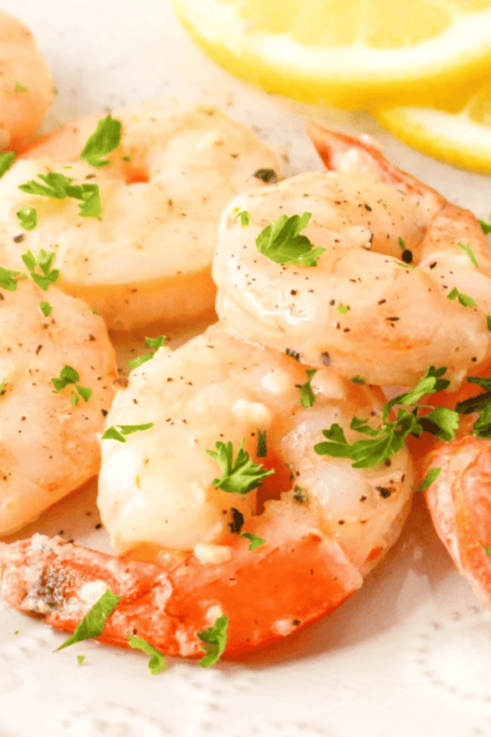 Close-up of pink, opaque cooked shrimp glistening with garlic butter sauce.