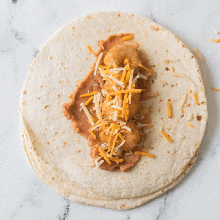 Mix cooked shredded chicken, sautéed onions, bell peppers, garlic, shredded cheese, and spices in a medium bowl until fully combined.