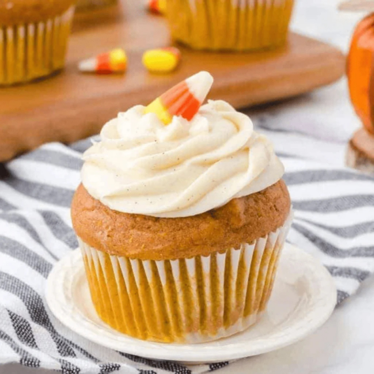 Frosted air fryer pumpkin spice cupcakes topped with cream cheese frosting and a dusting of cinnamon