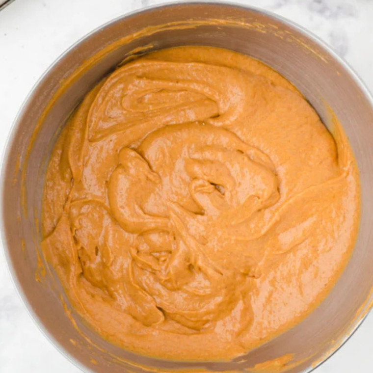 Pumpkin spice cupcake batter mixed smooth in a glass mixing bowl