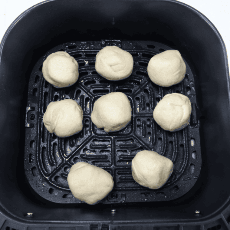 Air fryer basket sprayed and filled with hocus pocus buns ready to cook at 320°F