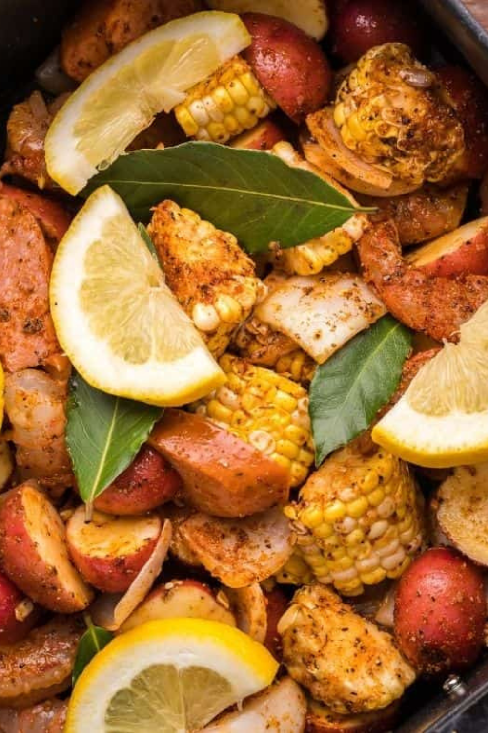 Homemade Old Bay seasoning copycat blend in a spice jar with measuring spoons and mixed spices nearby.