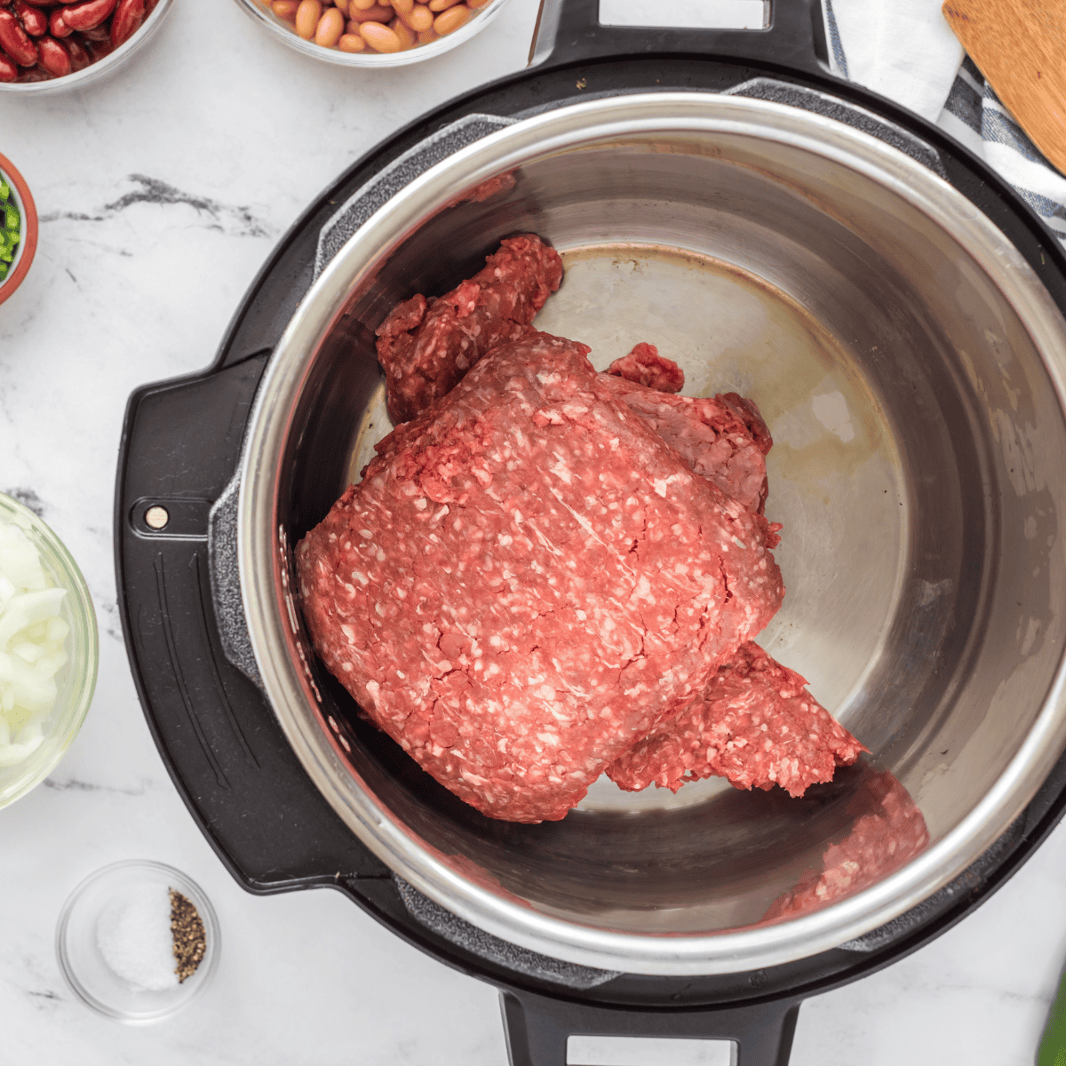 Raw ground beef, onion, garlic, and tomato sauce broken up in the Instant Pot for Cincinnati chili