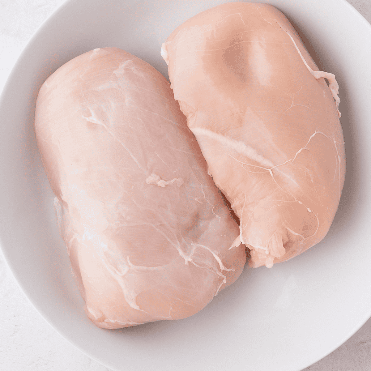 Ingredients for Instant Pot crack chicken: chicken breasts, cream cheese, ranch seasoning packet, bacon, and shredded cheddar on a table